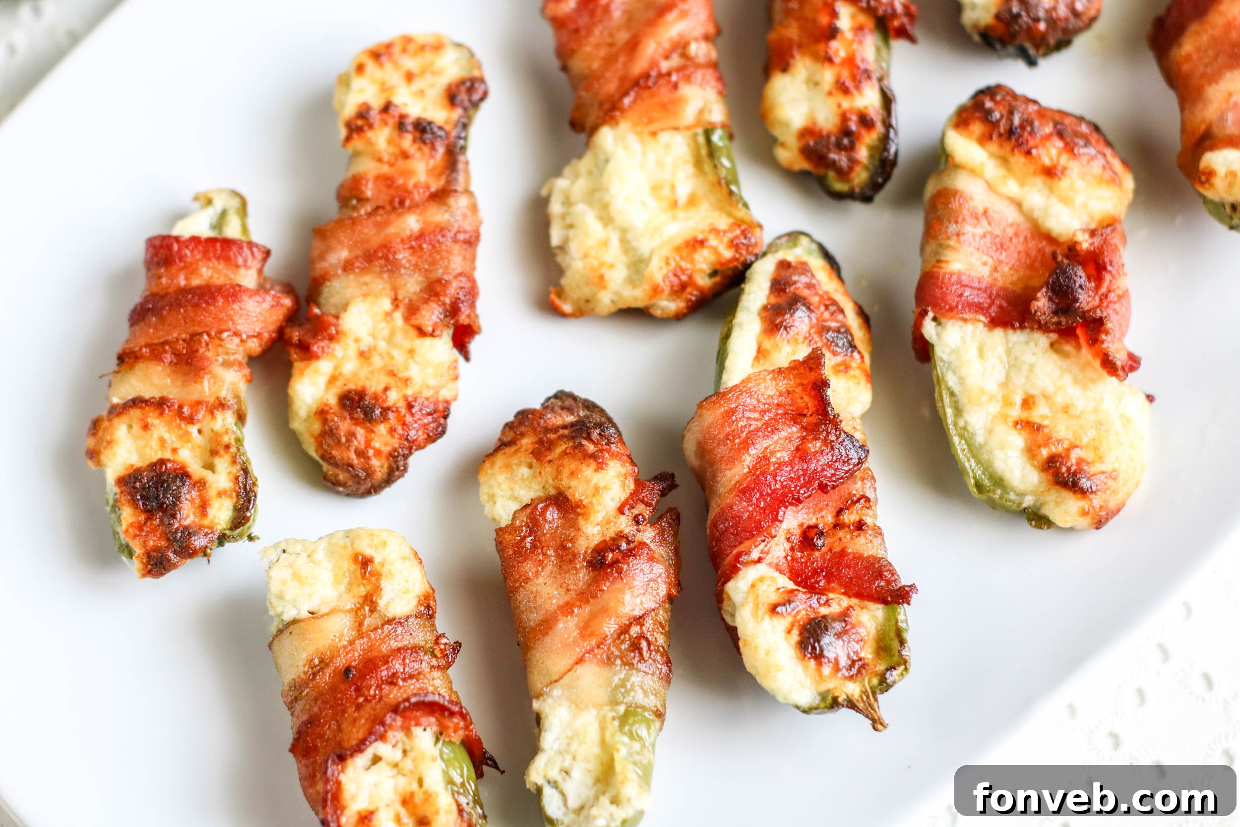Crispy Keto Air Fryer Bacon Jalapeño Poppers 4 Three perfectly cooked Air Fryer Bacon Wrapped Jalapeno Poppers, sliced in half to reveal the creamy cheese filling and golden-crisp bacon.