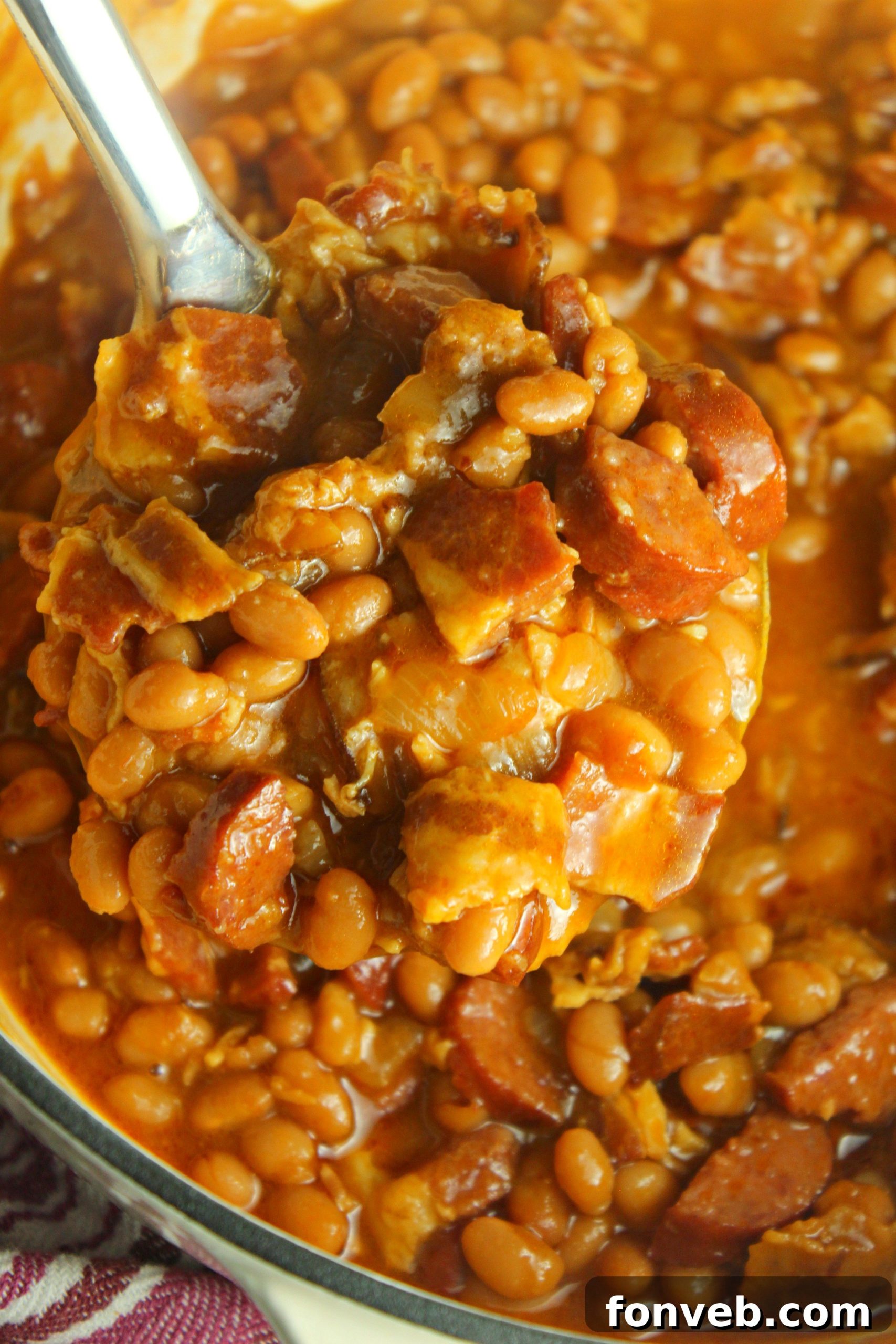 Signature Smoked Sausage Baked Beans 5 Close-up of baked beans with smoked sausage and bacon, showcasing rich texture