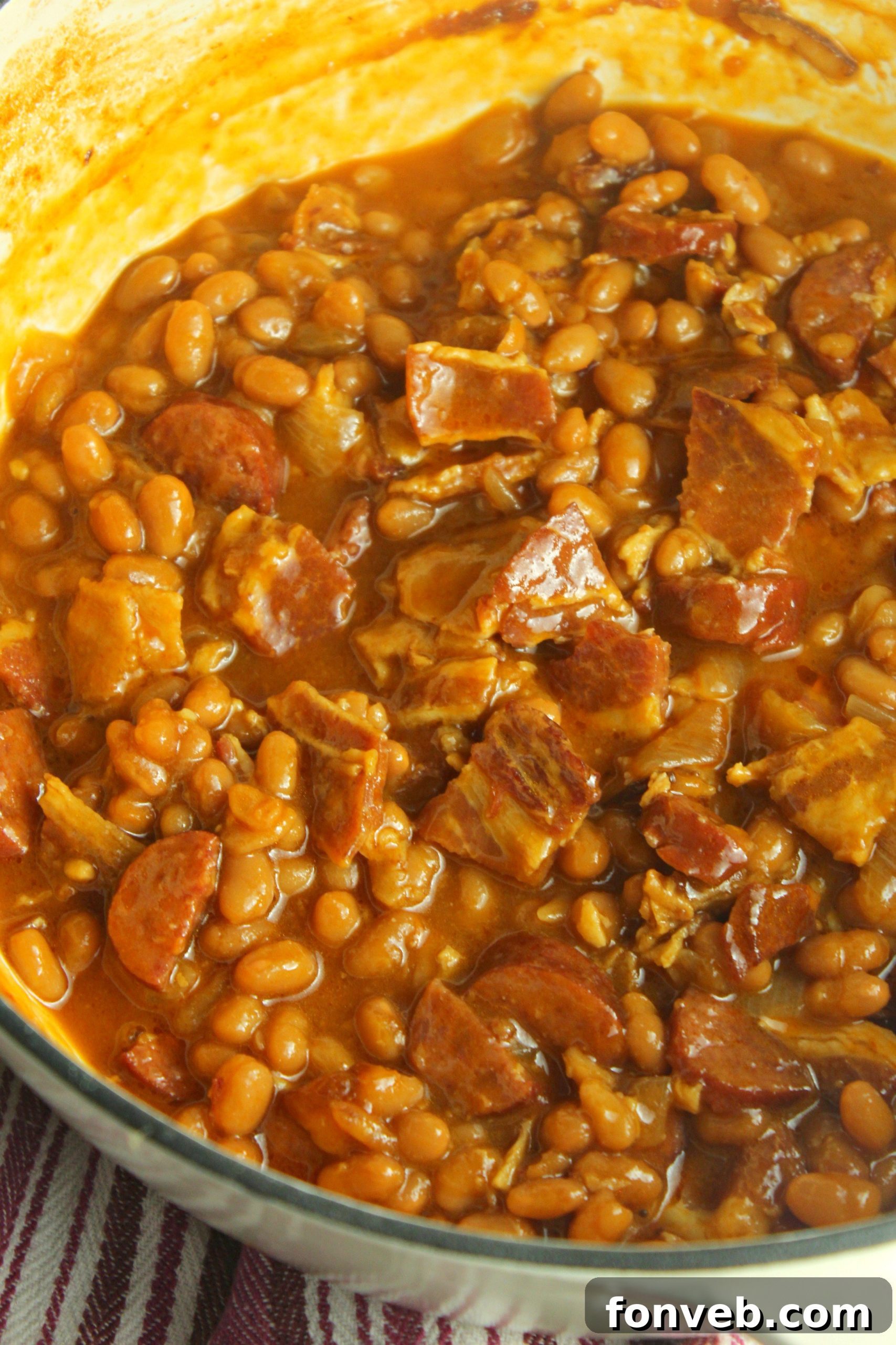 Signature Smoked Sausage Baked Beans 6 Another perspective of baked beans with smoked sausage and bacon in a red Dutch oven