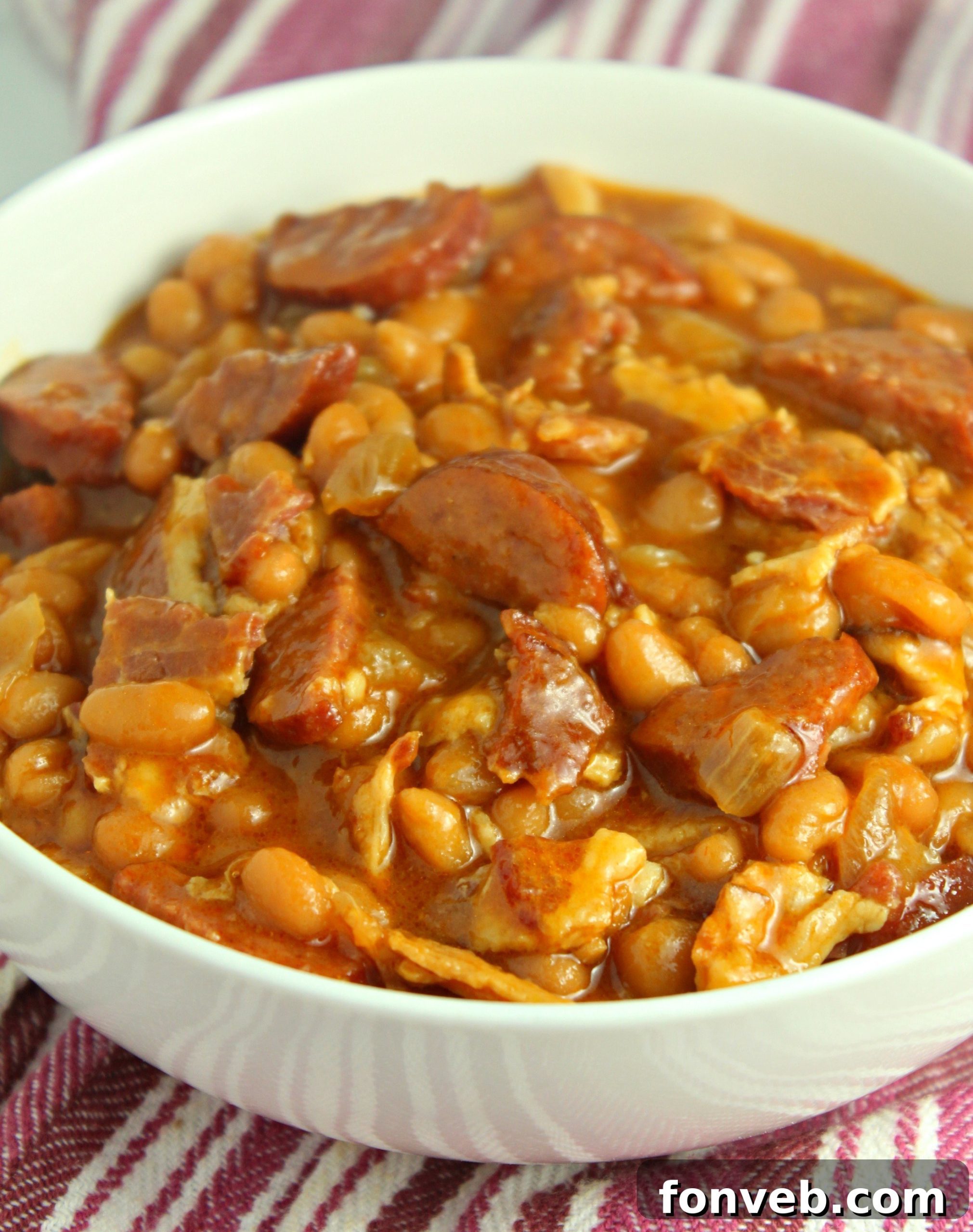Signature Smoked Sausage Baked Beans 7 Overhead shot of Ultimate Baked Beans with Smoked Sausage in a deep red pot, garnished with parsley