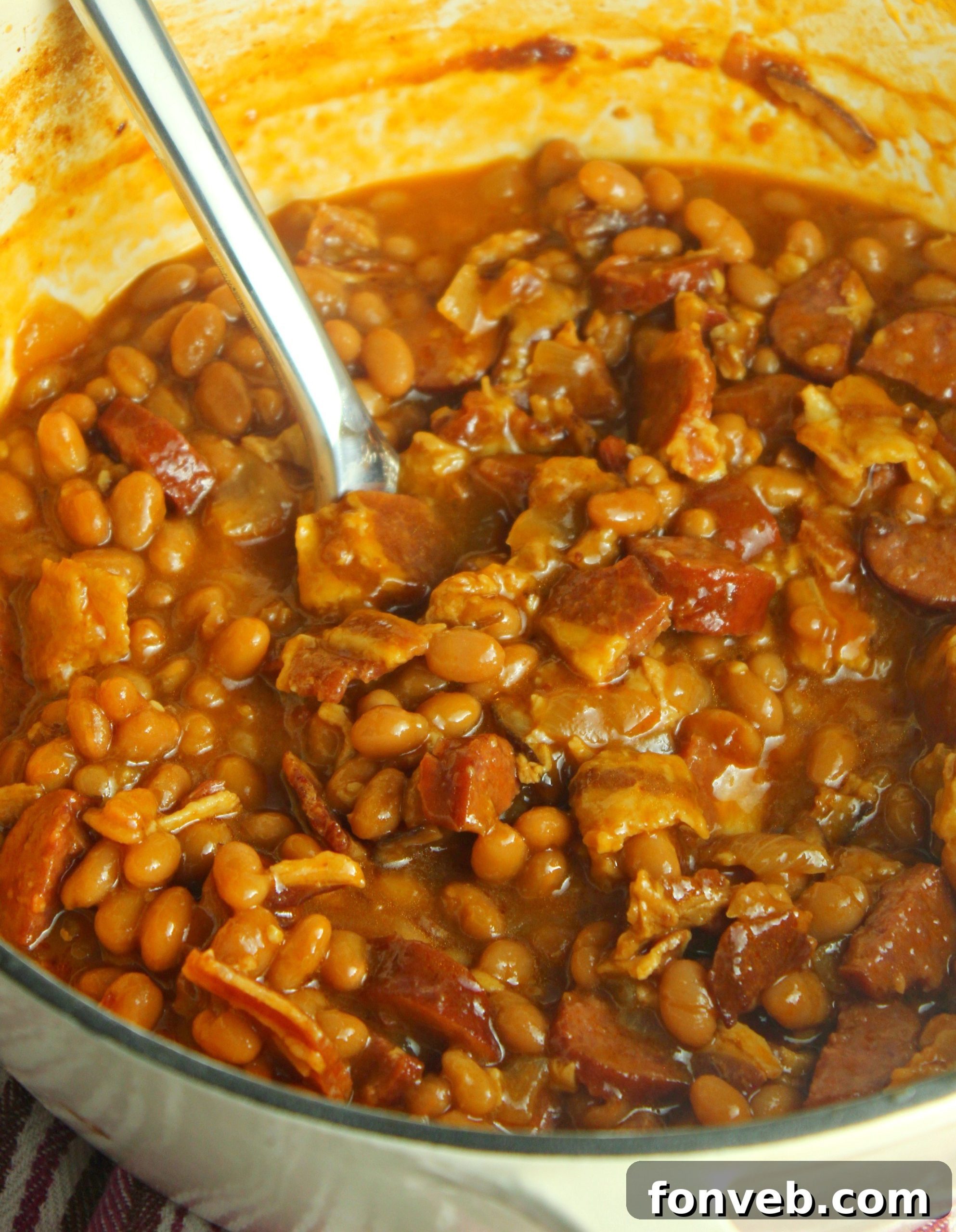 Signature Smoked Sausage Baked Beans 9 A close-up of a rustic spoon digging into the Ultimate Baked Beans with Smoked Sausage