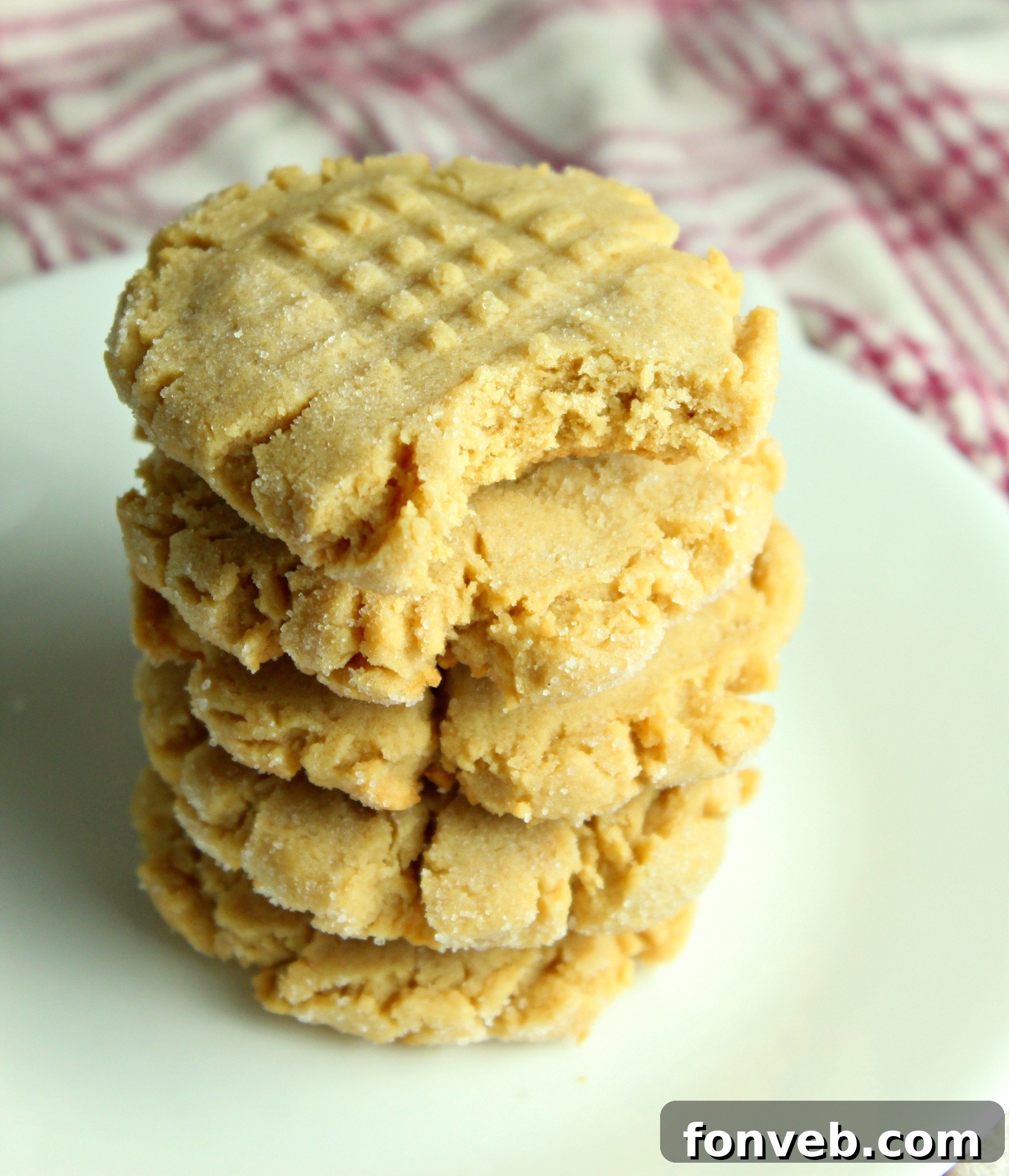 Freshly baked peanut butter cookies cooling on a wire rack, with some still on the baking sheet.