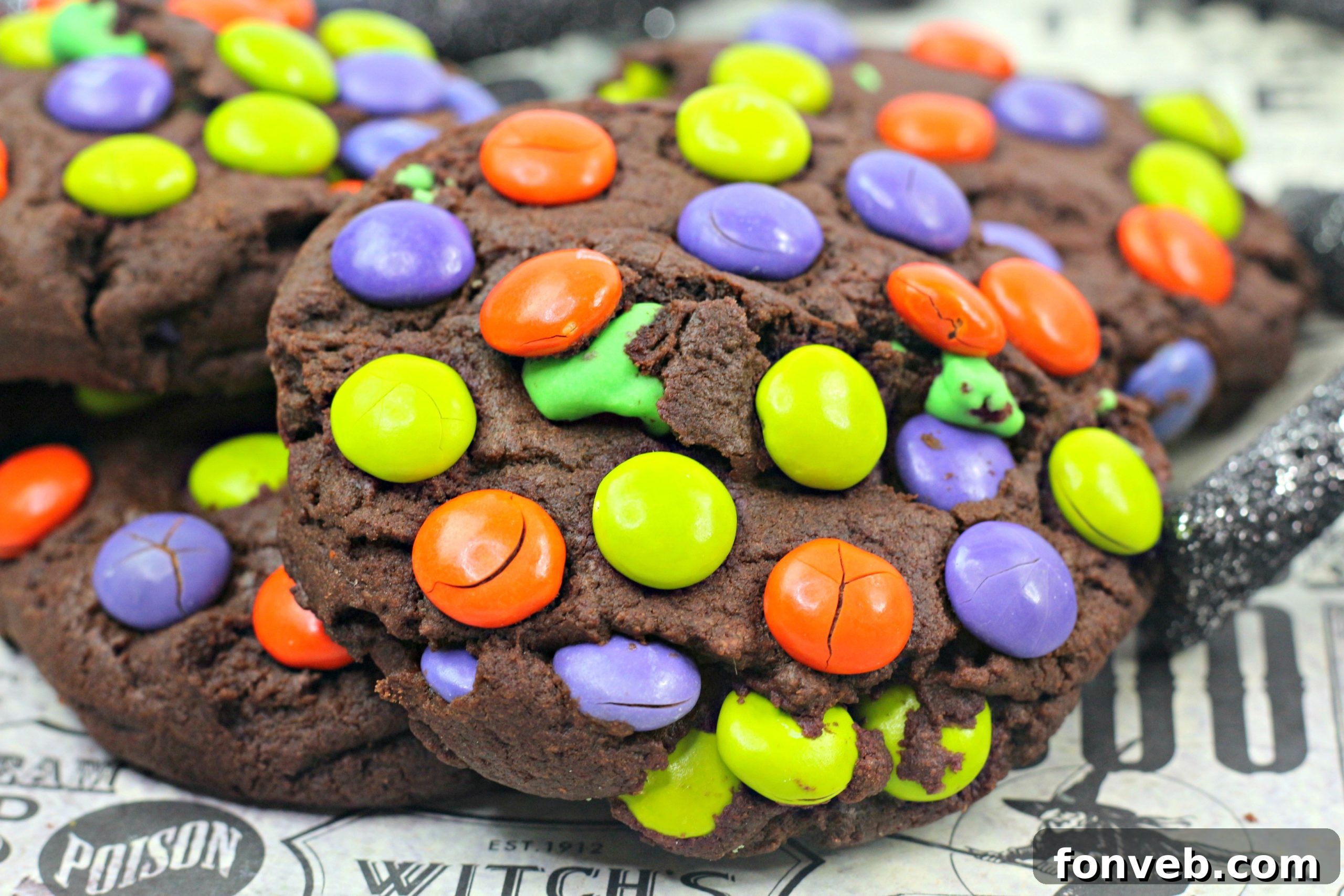 A close-up shot of a single Monster Mash Chocolate Cookie, showing its soft interior and colorful M&M inclusions.