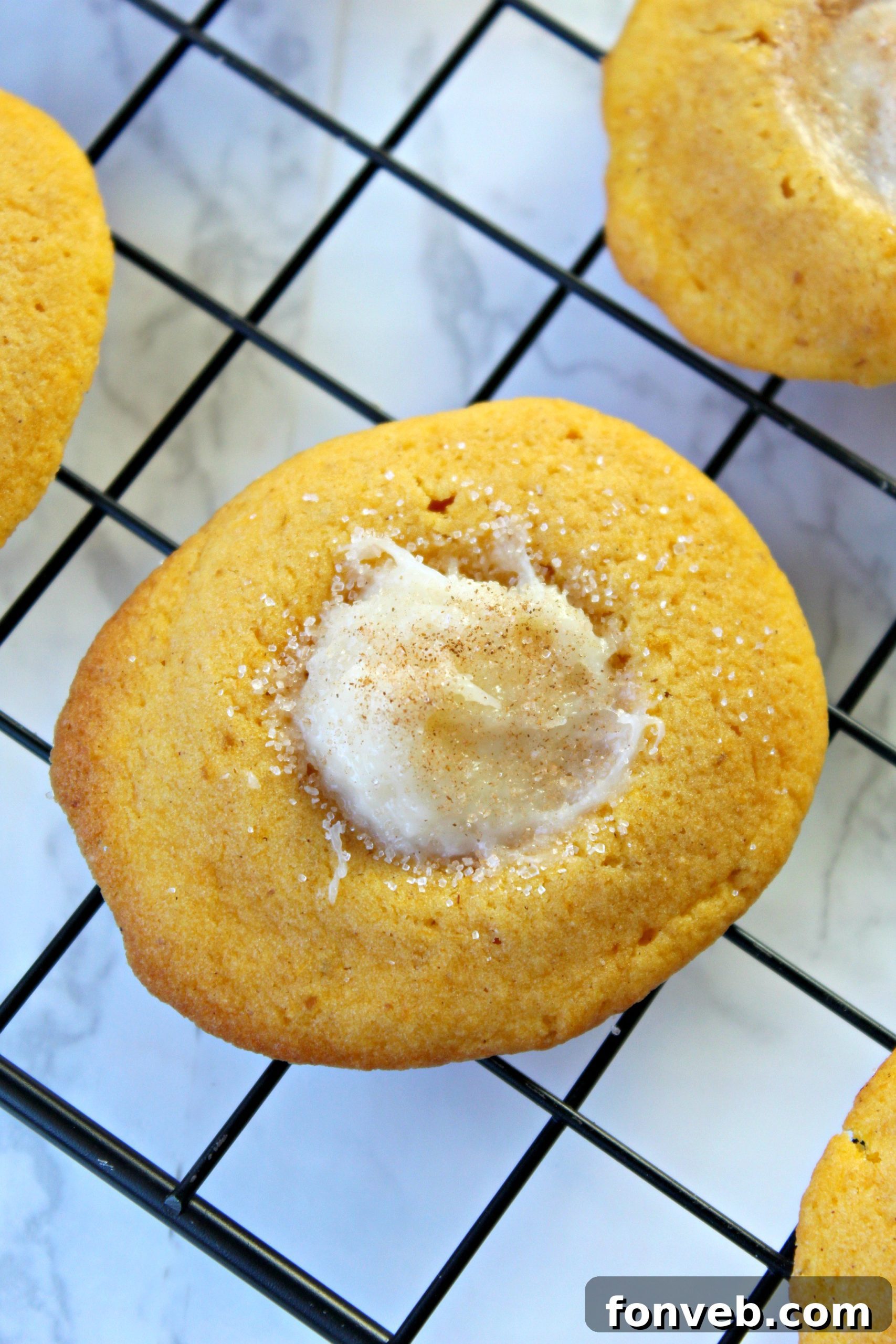 A batch of unbaked pumpkin cookie dough balls, some rolled in cinnamon sugar, ready for the oven.