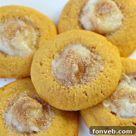 A close-up of a finished Pumpkin Cheesecake Thumbprint Cookie, showing the golden cookie and rich cheesecake.